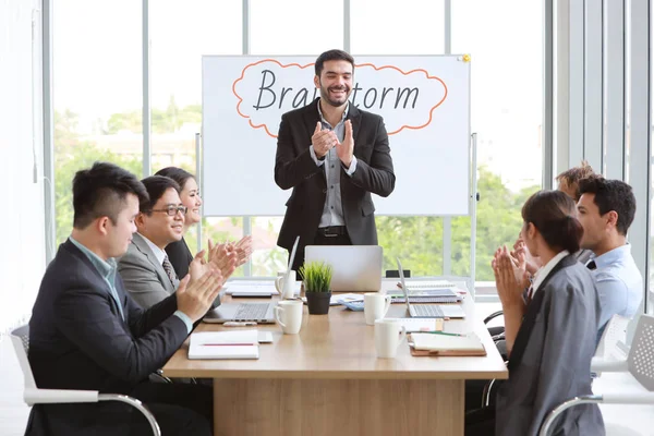 Conferencista caucásico dando una presentación pública con tema lluvia de ideas en la pizarra blanca en la sala de reuniones y la gente de negocios multiétnicos están prestando atención (concepto de formación o seminario ) — Foto de Stock