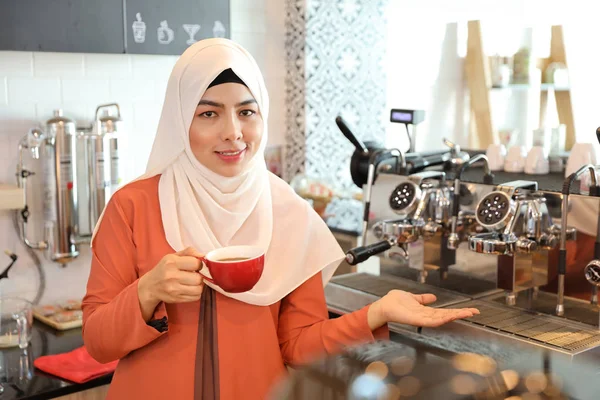 Jovem muçulmano barista menina fazendo café e mostrando negócio de sucesso em sua mão direita — Fotografia de Stock