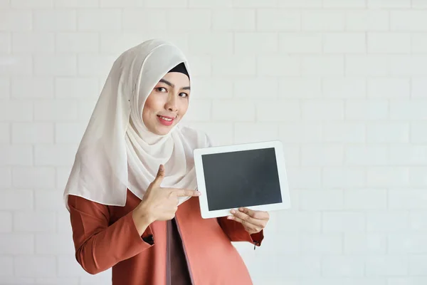 Jovem mulher de negócios muçulmana mostrando tela tablet em branco e apontando-o (você pode colocar carta sobre ele ) — Fotografia de Stock