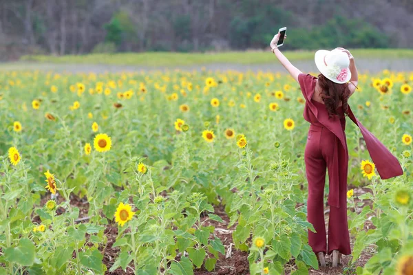 Красива жінка використовує смартфон під час відпустки серед квітів у природі — стокове фото