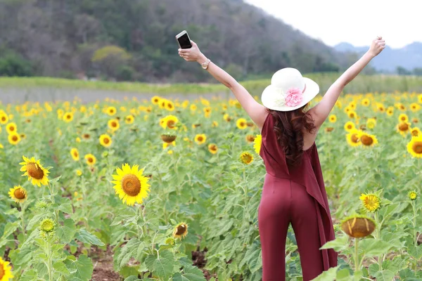 Doğada çiçek alanı arasında tatil tatil yaparken akıllı telefon kullanarak güzel kadın — Stok fotoğraf