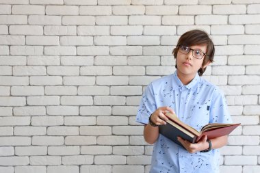 sevimli ve akıllı çocuk kitap tutan ve gözlük takan görünümlü ve bir şey düşünme