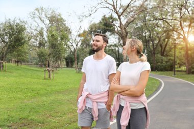 spor takım elbise giyen genç beyaz çift insanlar aşık. yaz sezonunda parkta yürüyüş ve konuşma 