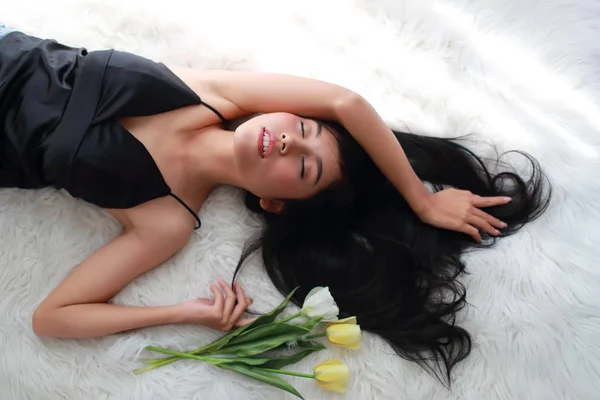 Mulher bonita e sexy deitar-se na cama com flores amarelas — Fotografia de Stock