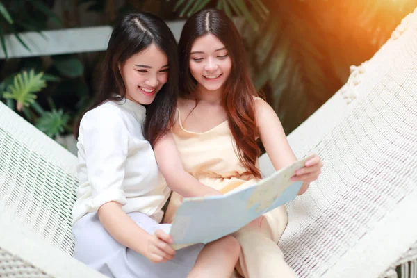 Genç ve sevimli Asyalı kadınlar bir hamak yalan ve tatil sırasında bir harita içinde yer arıyor — Stok fotoğraf