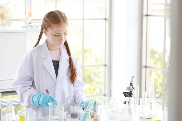 Curiosa niña está experimentando la ciencia con la cara de atención en tubo de ensayo colorido — Foto de Stock