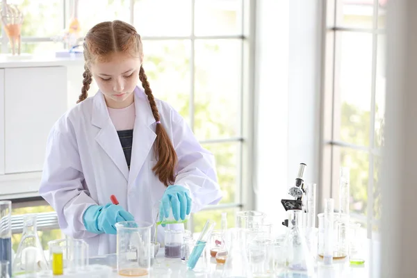 Curiosa niña está experimentando la ciencia con la cara de atención en tubo de ensayo colorido — Foto de Stock