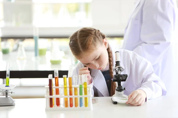 Curiosa niña está experimentando la ciencia con el microscopio y en —  Fotos de Stock