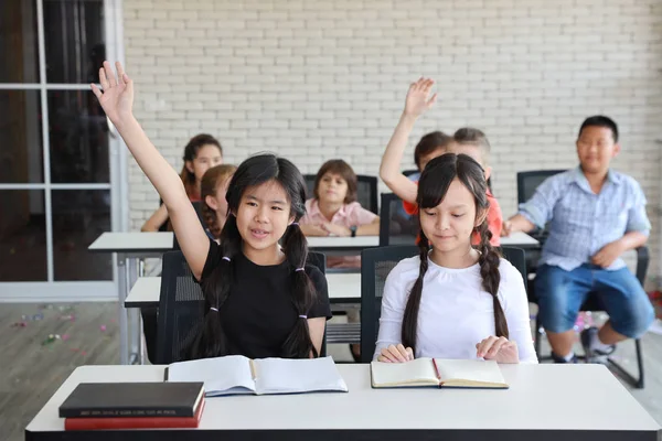 Liten flicka att höja händerna i klassrummet (utbildningskoncept) — Stockfoto