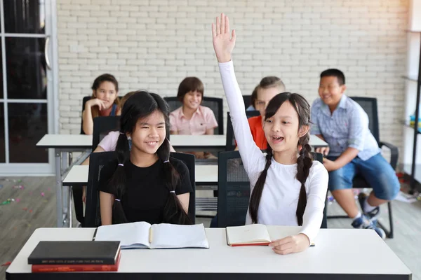 Liten flicka att höja händerna i klassrummet (utbildningskoncept) — Stockfoto