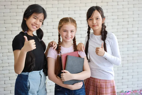 Grupo de meninas da escola segurando livros e mostrando polegar para cima — Fotografia de Stock