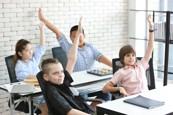 Grupp av skol barn att höja händerna i klassrummet (utbildning conce — Stockfoto