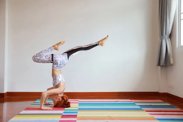 Esportivo jovem mulher caucasiana atraente em preto e branco sportswear praticando ou exercício de ioga interior. equilíbrio entre corpo e mental. (conceito de vida saudável) — Fotografia de Stock
