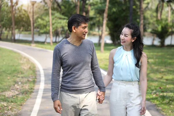 Asiático pareja caminando y hablando en el parque con feliz cara —  Fotos de Stock