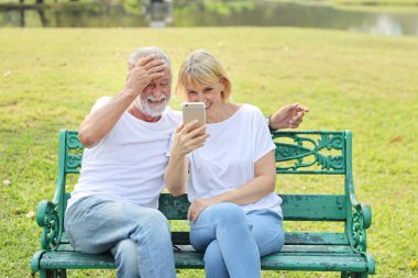 Yaşlı beyaz çift, akıllı telefondan gelen görüntülü aramayı gülümseyerek dijital bağımlılık yapan sosyal çağlardır.