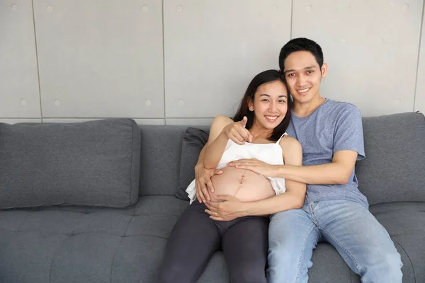 Junger Mann umarmt junge asiatische schwangere Frau und ihren Bauch — Stockfoto
