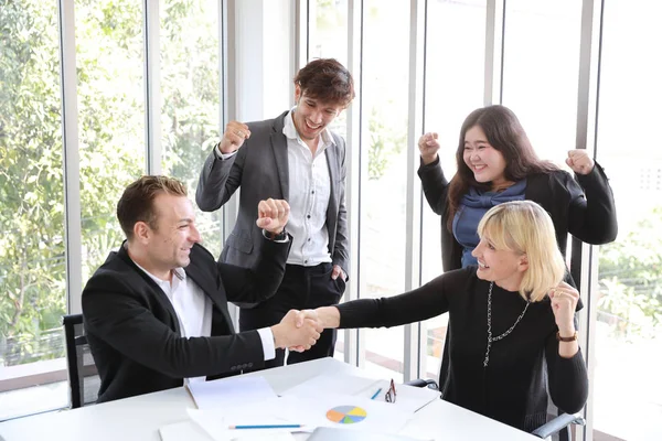 Kaukasiska och asiatiska affärsman visar framgång Business Profit Graph i mötet då de lägger sina händer upp och skakar hand innebörden av deras jobb är framgång med leende och glada ansikten. — Stockfoto