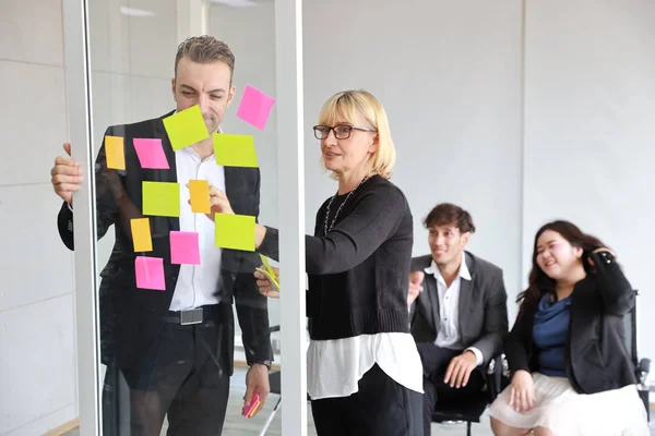 Multietniska affärsmän som använder post det anteckningar för brainstorming eller dela idé i nya projektmöte — Stockfoto