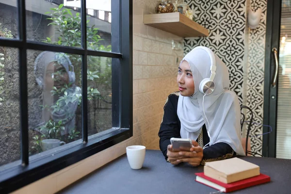 年轻的穆斯林女商人坐在咖啡店，而听 — 图库照片