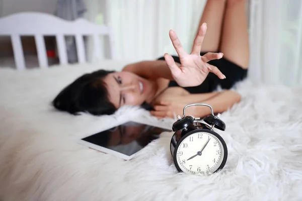 若い女性は目覚まし時計が遅く起きるのを止めようとする — ストック写真