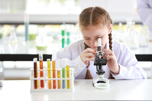 Ευτυχισμένο μικρό καυκάσιο κορίτσι κάνοντας πειράματα επιστήμης με μικροσκόπιο (εκπαίδευση και επιστήμονας έννοια) — Φωτογραφία Αρχείου