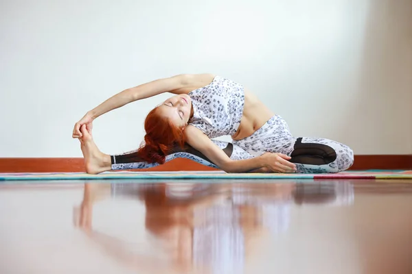 Zijaanzicht van jonge aantrekkelijke blanke vrouw in zwart-wit sportkleding oefenen of yoga-oefeningen indoor. evenwicht tussen lichaam en geest. (concept van gezond leven) — Stockfoto