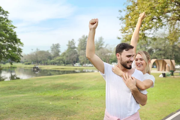 年轻夫妇相爱了在夏季，在公园内放松，手举双手，带着快乐和笑脸（友谊或情人节概念）) — 图库照片