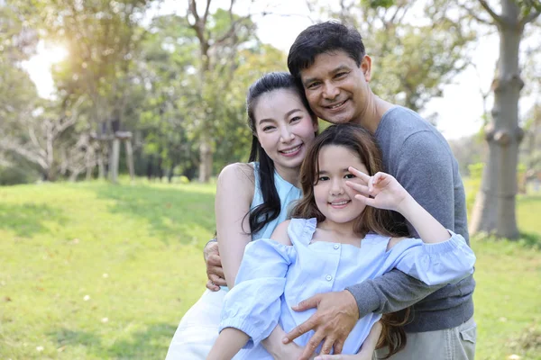 Bild av lycklig familj, dotter som visar seger symbol på händerna med leende under sommaren i parken — Stockfoto