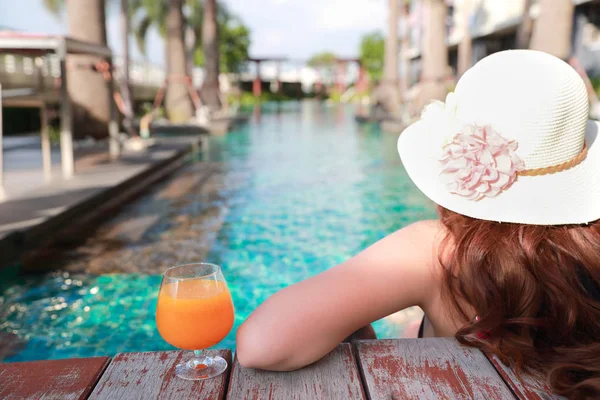 Retrato de mujer hermosa y sexy disfrutar de vacaciones con jugo de naranja en la piscina — Foto de Stock