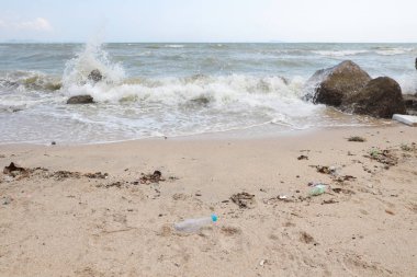 kirli kumlu plajda plastik kirliliği, çöp ve atık dolu kirli plajda boş plastik su şişesi açı görünümü görüntü