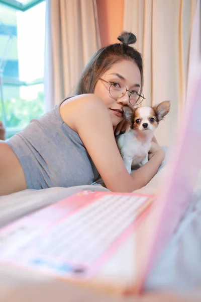 Belle et sexy femme à l'aide de téléphone cellulaire et jouer avec chien chiot mignon sur le lit — Photo