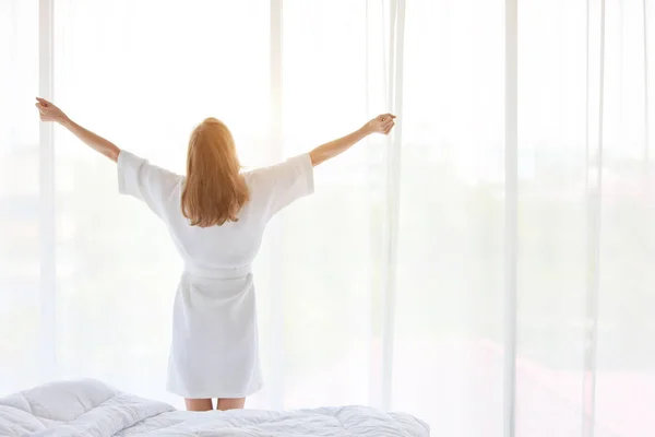 Una buona forma e una giovane ragazza sana si svegliano al mattino all'alba e in piedi e si allungano alla finestra in camera da letto — Foto Stock
