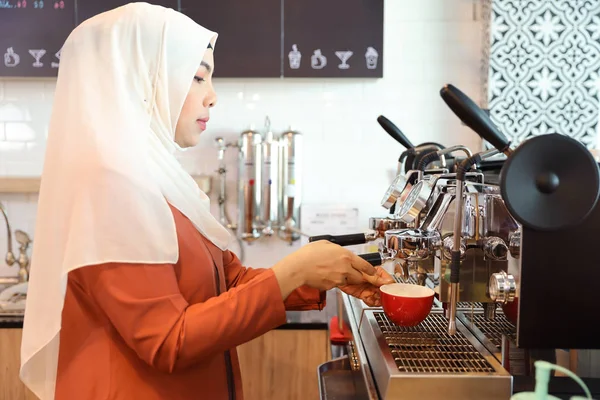 Giovane donna musulmana barista che fa il caffè con la faccia concentrazione — Foto Stock
