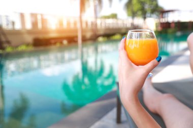 güzel ve seksi kadın elleri yüzme havuzunda portakal suyu ile tatil tatil keyfini çıkarın