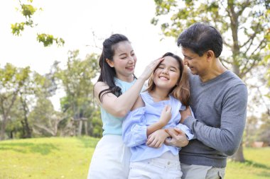 mutlu asya lı aile görüntüsü, parkta yaz aylarında gülümseyerek mutlu anne yanak gülerek kızı