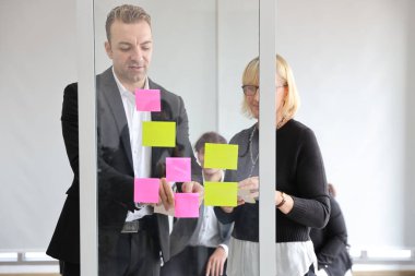 Yeni proje toplantısında fikir alışverişinde bulunmak veya fikir alışverişinde bulunmak için notlar kullanan çok ırklı iş adamları 