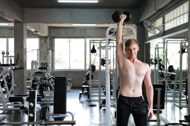 Yakışıklı beyaz adam gülümseyen yüzü ile fitness bir dambıl kaldırma