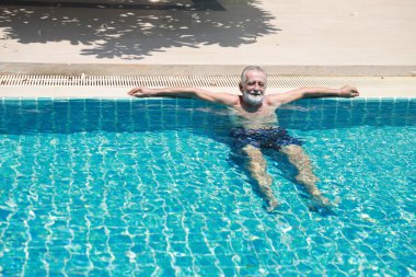 Emeklilik tatilinde havuzda yüzerken dinlenen ve gülümseyen mutlu bir beyaz.