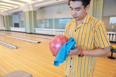genç asyalı adam tutma ve spor kulübünde bowling topu temizleme