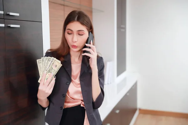 Красива бізнес-леді портрет сюрприз і тримає гроші з мобільним телефоном — стокове фото
