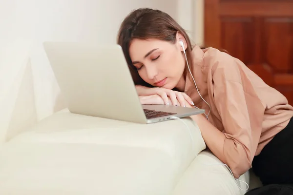 Jeune femme écouter de la musique de l'ordinateur et s'endormir sur le canapé dans le salon — Photo