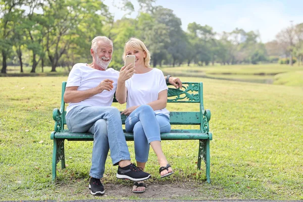 elderly couple laughing while using video call from smart phone to grandchild