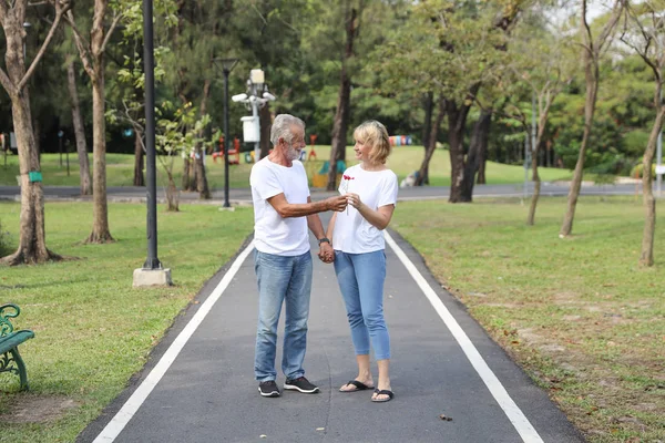 Full längd sköt kaukasiska Senior man ger överraskning blomma till sin fru för bröllopsdag i Park Outdoor (Valentine eller kärlek Concept) — Stockfoto