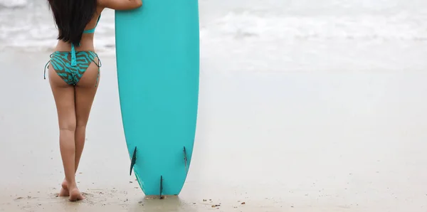 Rückansicht von sexy und schönen Surfermädchen Po, die grünen Bikini tragen und Surfbrett auf tropischem Meer in grünem Badeanzug im Sommer am Sandstrand mit dem richtigen Kopierraum halten (Sportkonzept) — Stockfoto