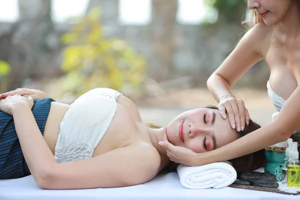 Face massage, side view portrait of two young beautiful and sexy asian women, long hair with white dress enjoying oil spa massage salon while lying during summer holiday vacation — Stock Photo, Image