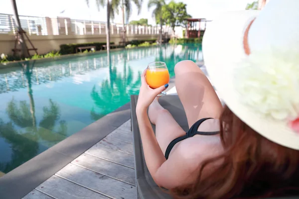 Portret pięknej i seksownej kobiety cieszyć wakacje z sokiem pomarańczowym w basenie — Zdjęcie stockowe