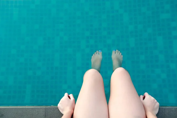 Piernas de mujer en la piscina en vacaciones — Foto de Stock