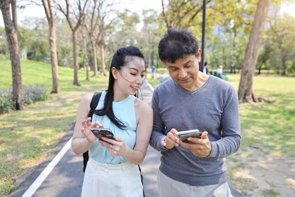 Asiatische Mann und Frau sind digital süchtig sozialen Zeitalter durch die Nutzung des Internets von Handy die ganze Zeit beim Spaziergang im Park — Stockfoto