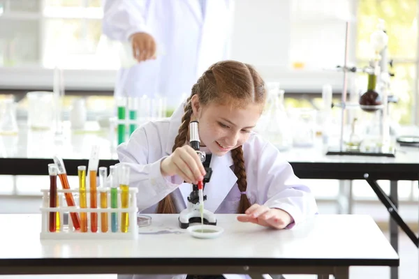Ciekawa dziewczyna dziecko zabawy na eksperymenty naukowe z mikroskopem i uśmiechniętą twarzą (edukacja i koncepcja naukowca) — Zdjęcie stockowe