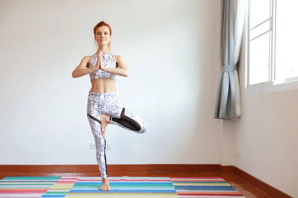 Giovane donna caucasica attraente sportiva in abbigliamento sportivo in bianco e nero che pratica o esercita yoga al coperto. equilibrio tra corpo e mente. (concetto di vita sana) — Foto Stock